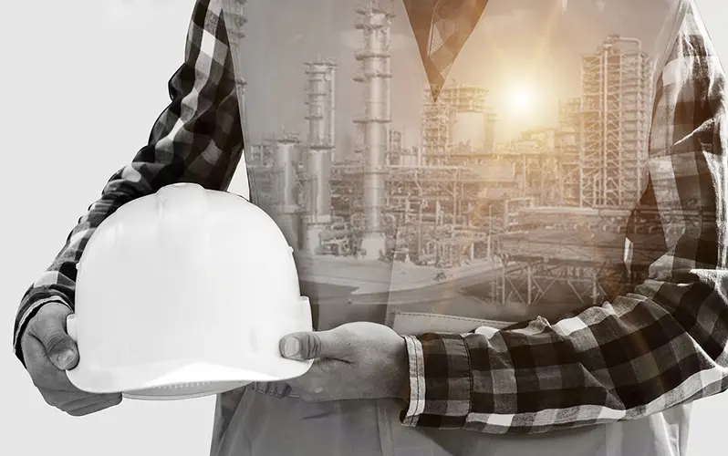 la prévention de l'environnement au sein d'une usine: Photo d'un contremaître tenant son casque et en arrière plan une usine en fonctionnement